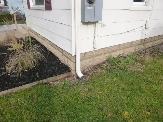 Downspout pouring water around the exterior walls of the home.